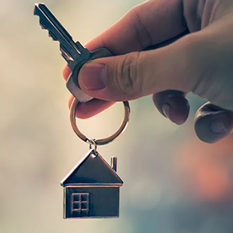 Foto de mão segurado uma chave com chaveiro em formato de casa